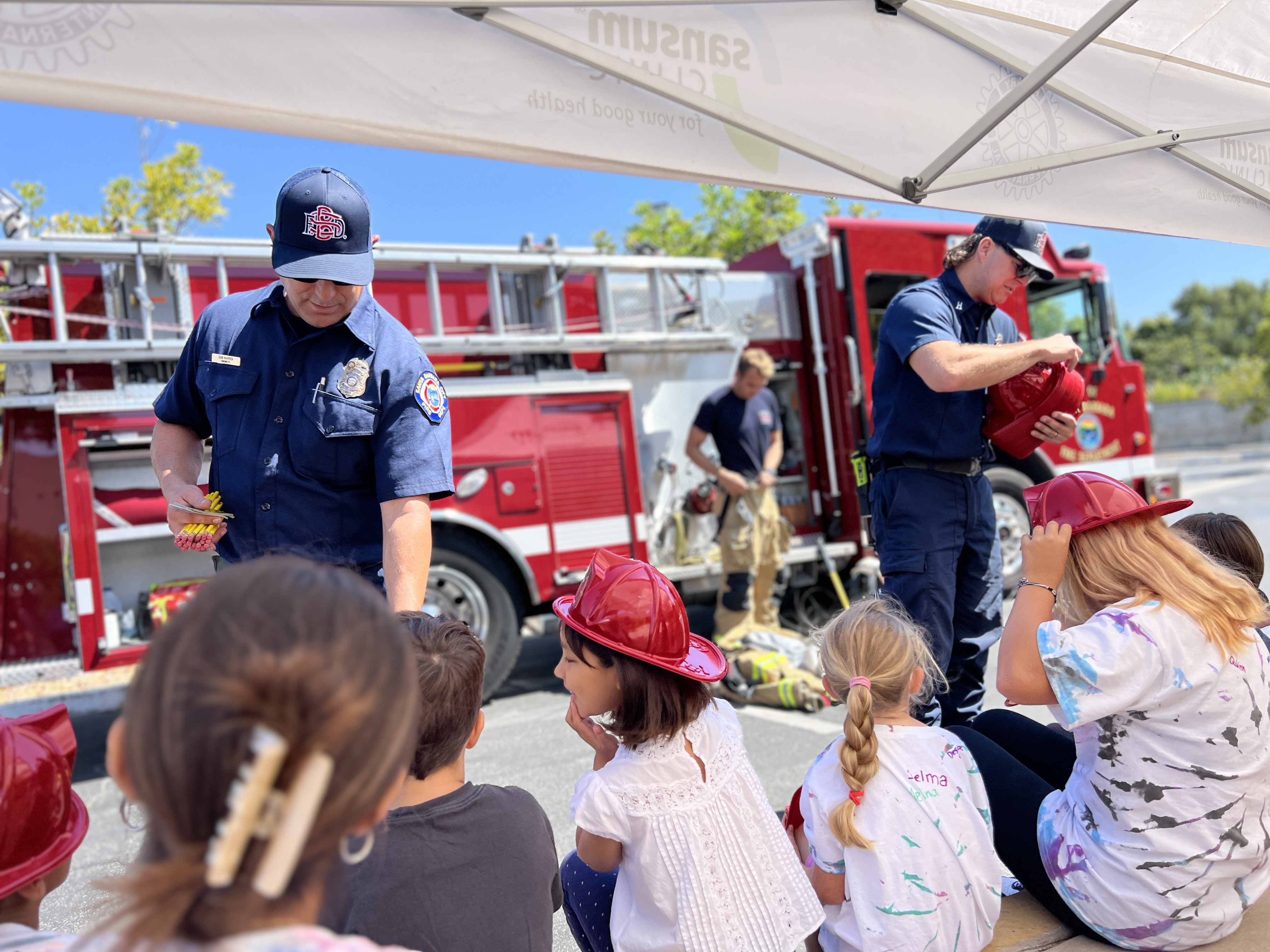 Firefighters giving out hats to campers